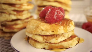 Fluffy pancakes stacked with syrup and raspberries