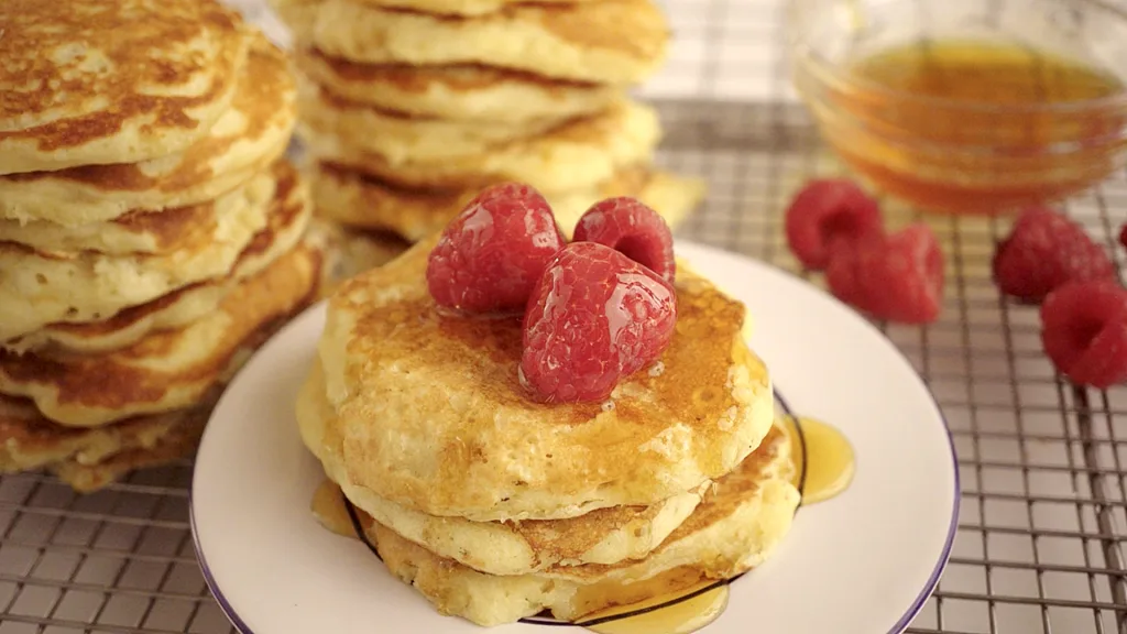 Fluffy pancakes stacked with syrup and raspberries