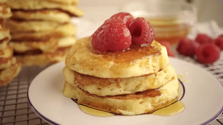 Fluffy pancakes stacked with syrup and raspberries