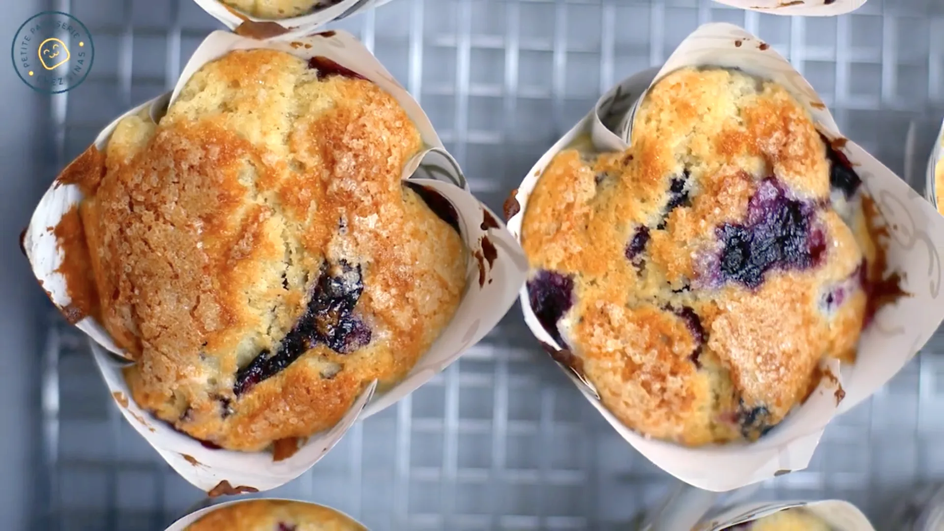 Close-up of golden-topped Jordan Marsh blueberry muffins cooling on a wire rack.
