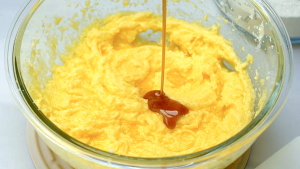 Creamy blueberry muffin batter being mixed in a glass bowl.