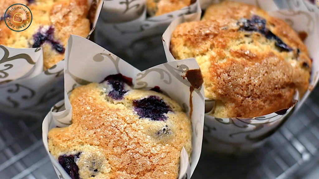 Close-up of golden-topped Jordan Marsh blueberry muffins cooling on a wire rack.