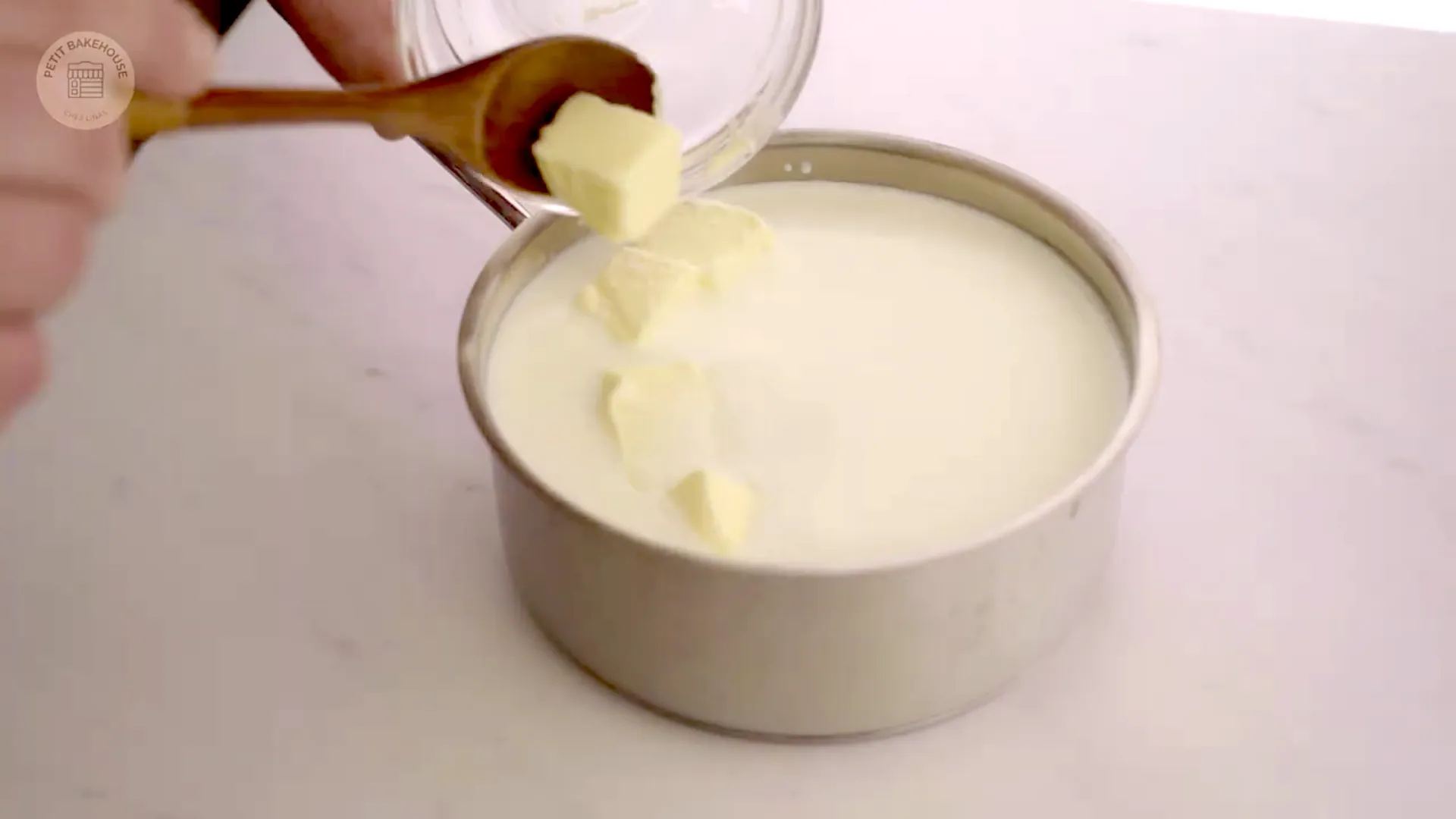 Butter being added into milk in a saucepan ready to go on the stove
