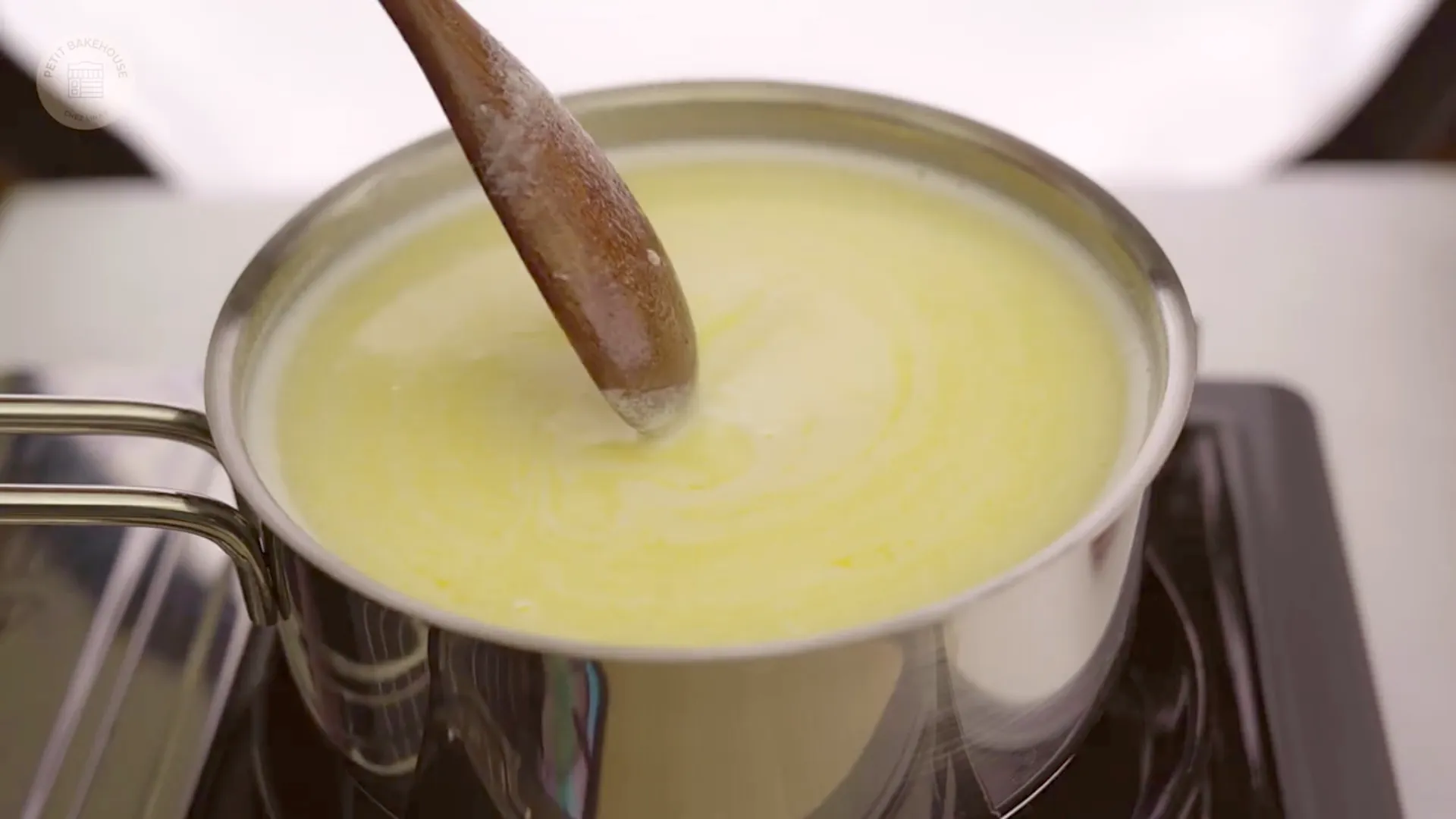 Vanilla and sugar being stirred into the warm milk mixture with a spoon
