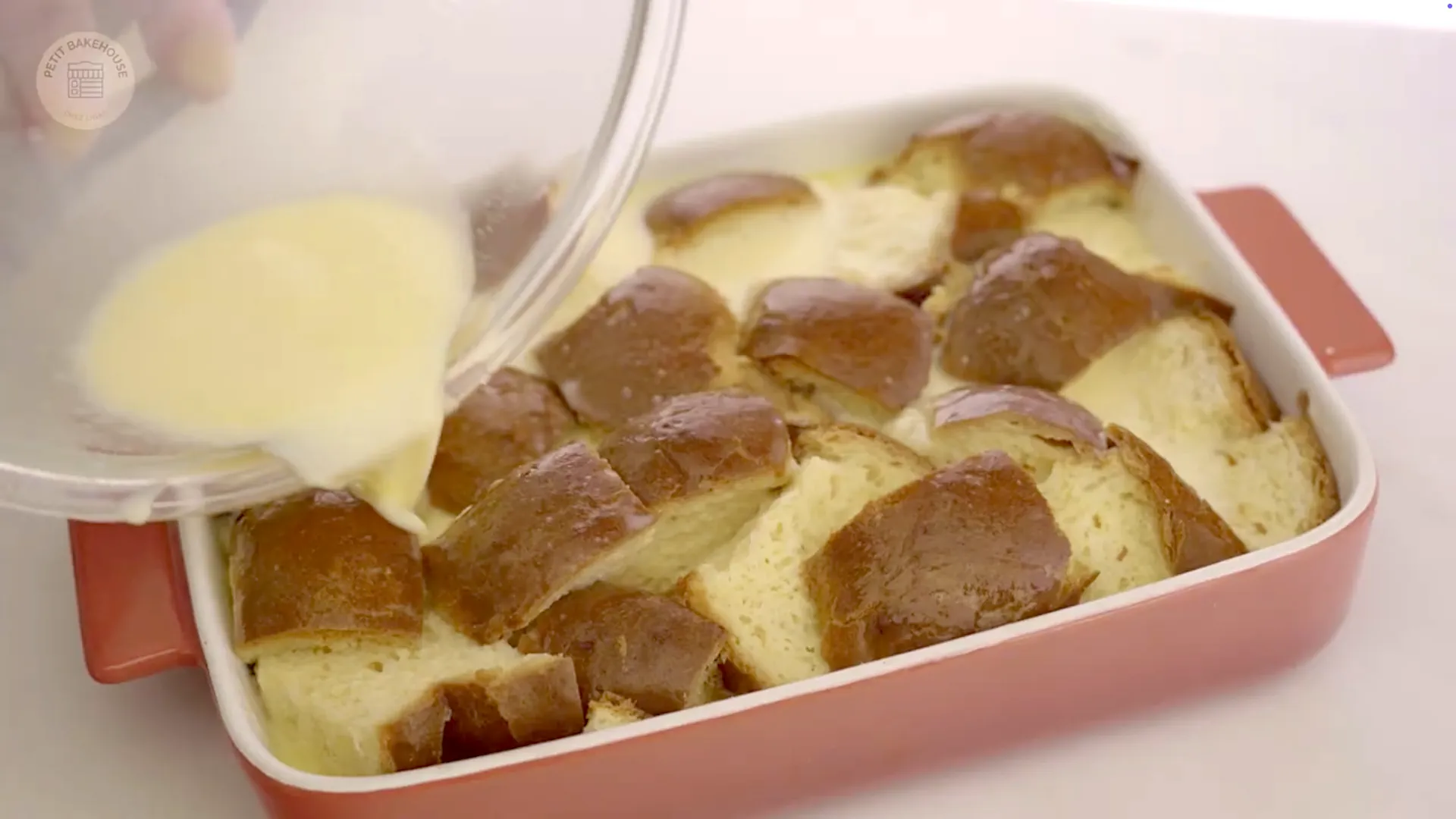 Custard being poured evenly over the bread cubes, soaking them