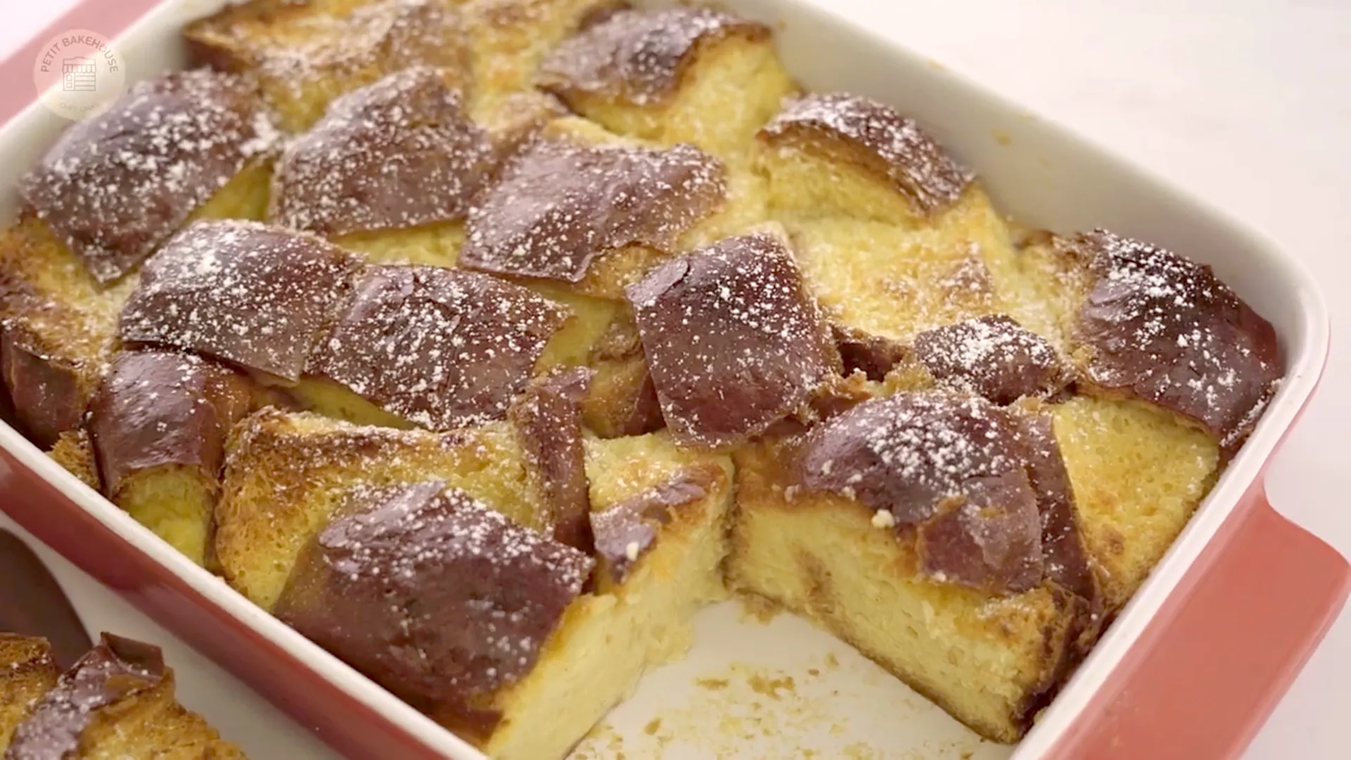 Overhead view of bread pudding on a linen towel with serving utensils nearby